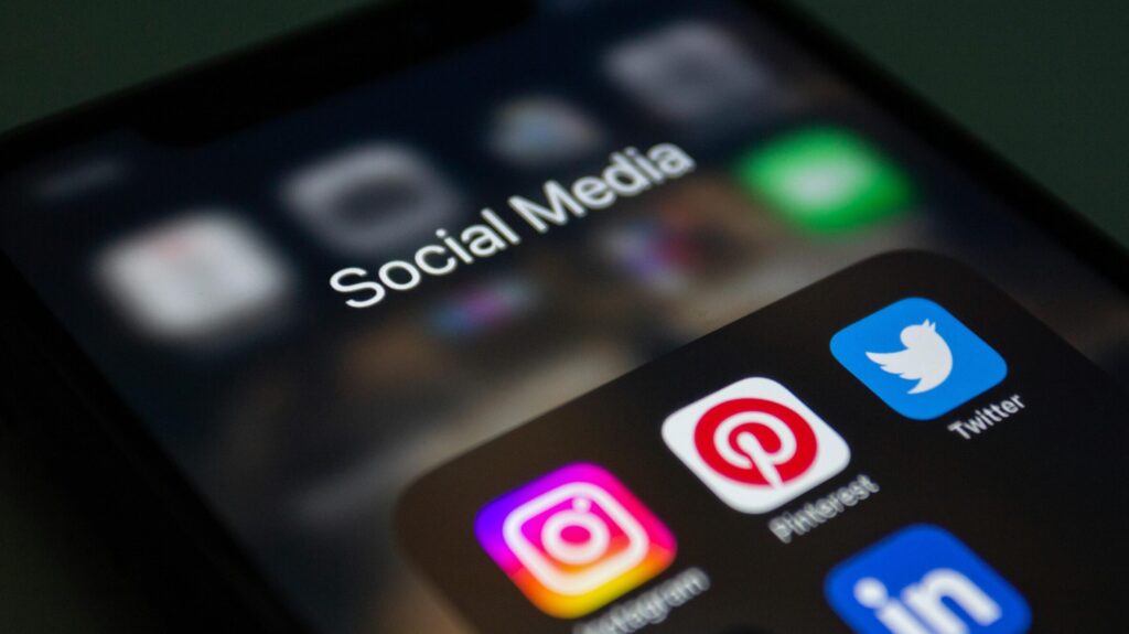 Social media app icons including Instagram, Pinterest, Twitter, and LinkedIn on a smartphone screen.